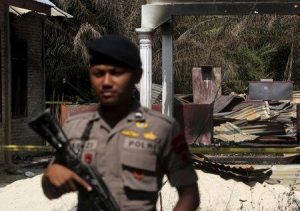 A policeman holds a rifle as he stands guard in front of a burned church at Suka Makmur Village in Aceh Singkil