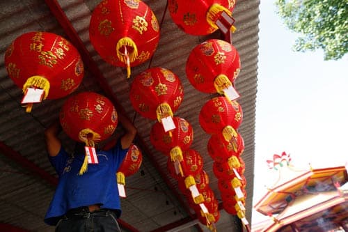 A caretaker hangs a lantern at a temple ahead of Chinese New Year celebrations in Jakarta